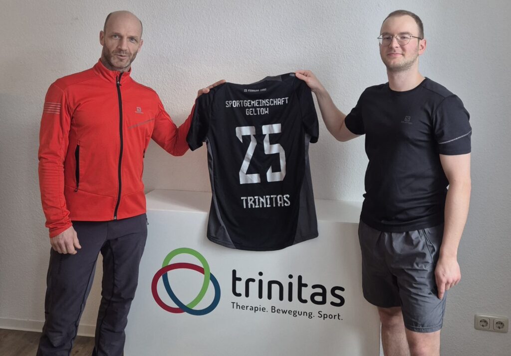 zwei Mitarbeiter halten das neue Trikot für die SG Geltow