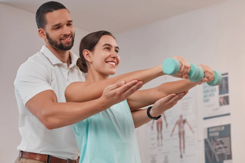 Physiotherapeut hilft einer Patienten bei Armübungen mit Hanteln