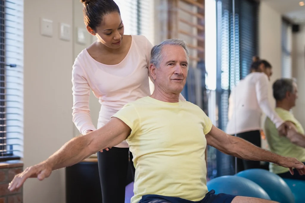 Moderne Physiotherapie-Praxis mit einem Patienten, der an einer rehabilitativen Trainingstherapie teilnimmt. Medizinische Geräte unterstützen den Wiederaufbau der Muskulatur nach Verletzungen oder Operationen.
