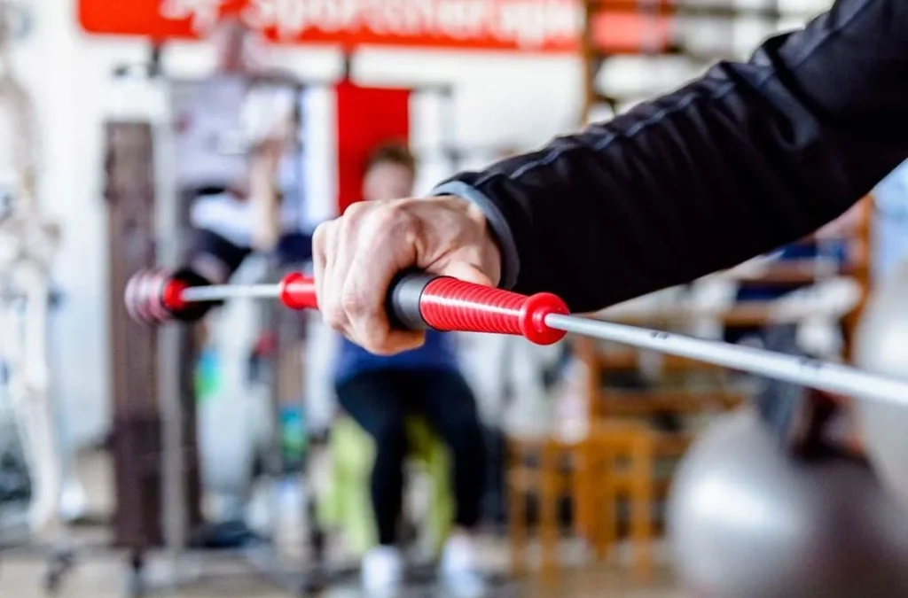 Rechte Hand mittig zentriert im Bild, die während der Physiotherapie einen Flexstab in der Hand hält